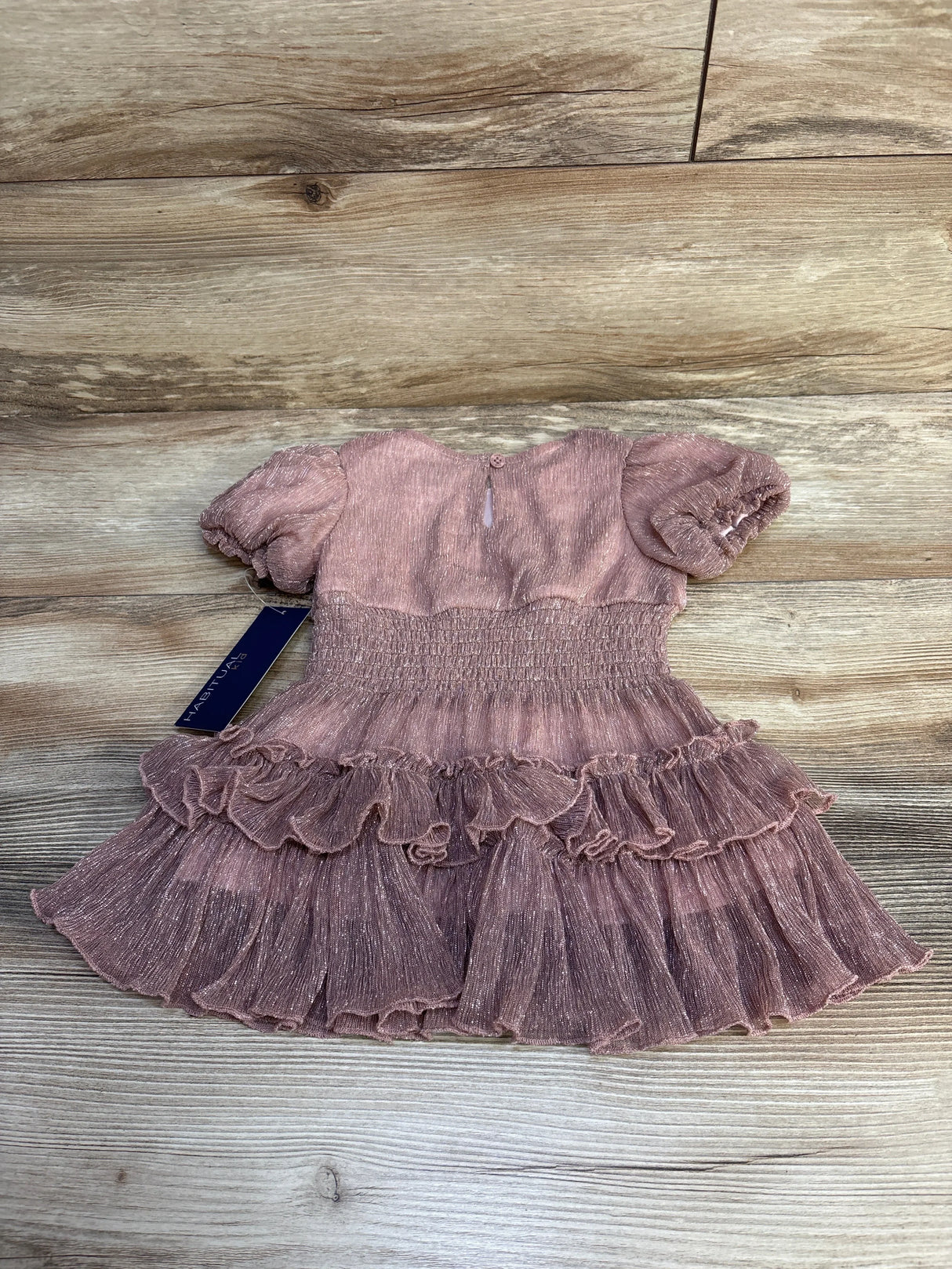 Pink toddler dress with puff sleeves and ruffled skirt on wooden floor