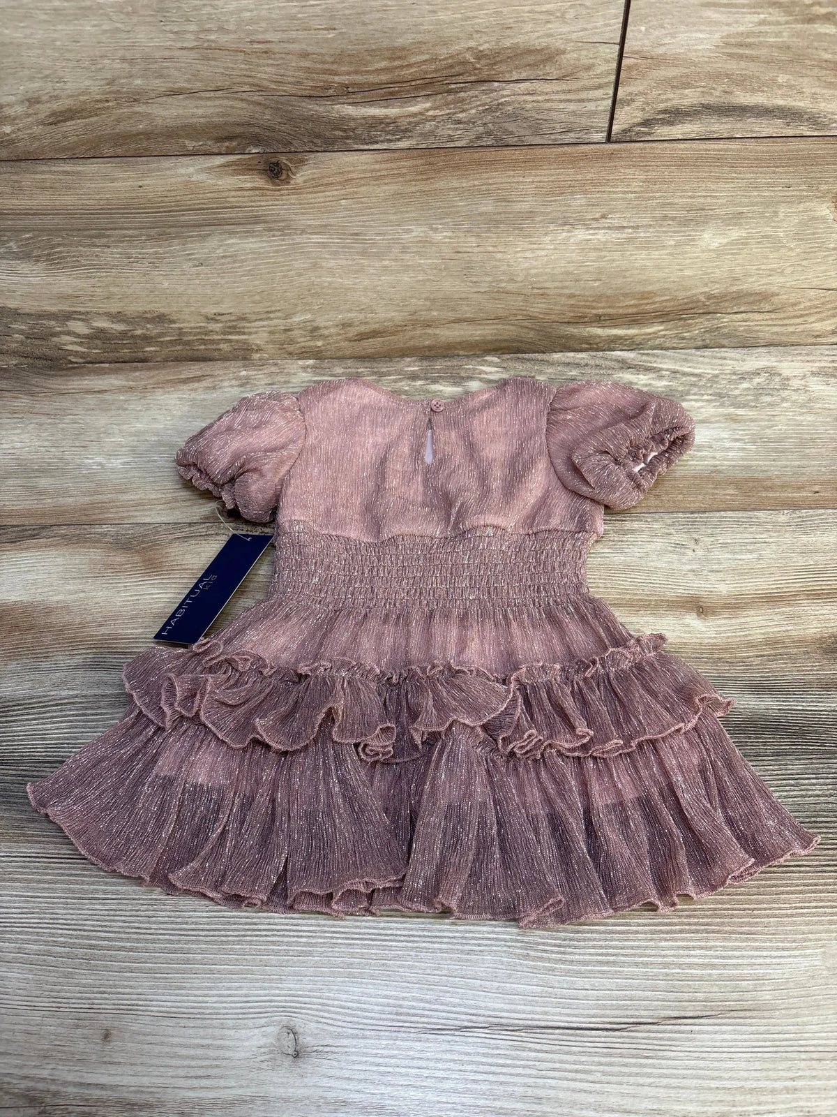 Pink toddler dress with puff sleeves and ruffled skirt on wooden floor