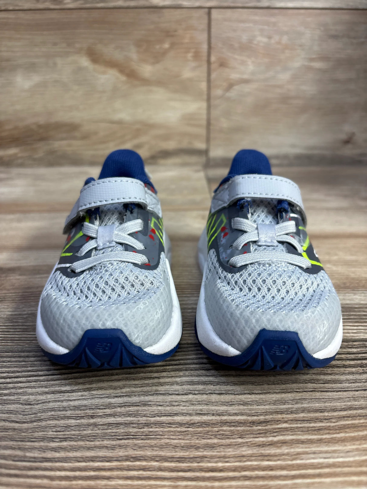 Gray mesh New Balance kids' sneakers with blue accents on wood floor