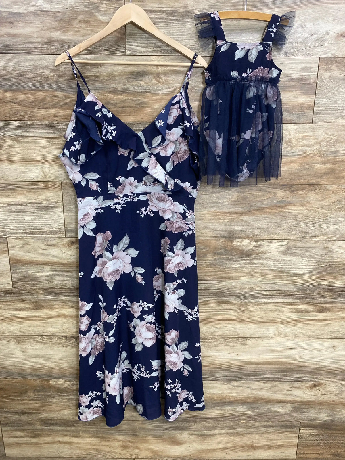 Front view of navy floral matching mom and child dresses showcasing the mom maxi length and ruffle details on wood backdrop
