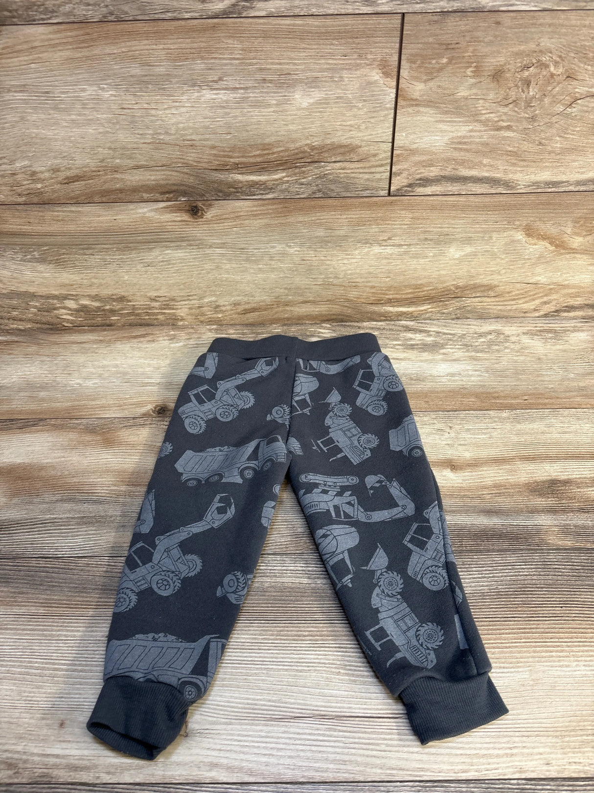 Dark gray toddler joggers with construction vehicle print on wood background