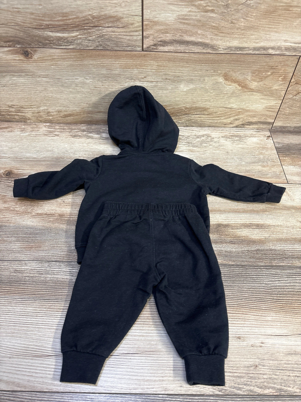 Black Nike 2-piece zip-up hoodie and joggers set for baby size 3m on a wood background