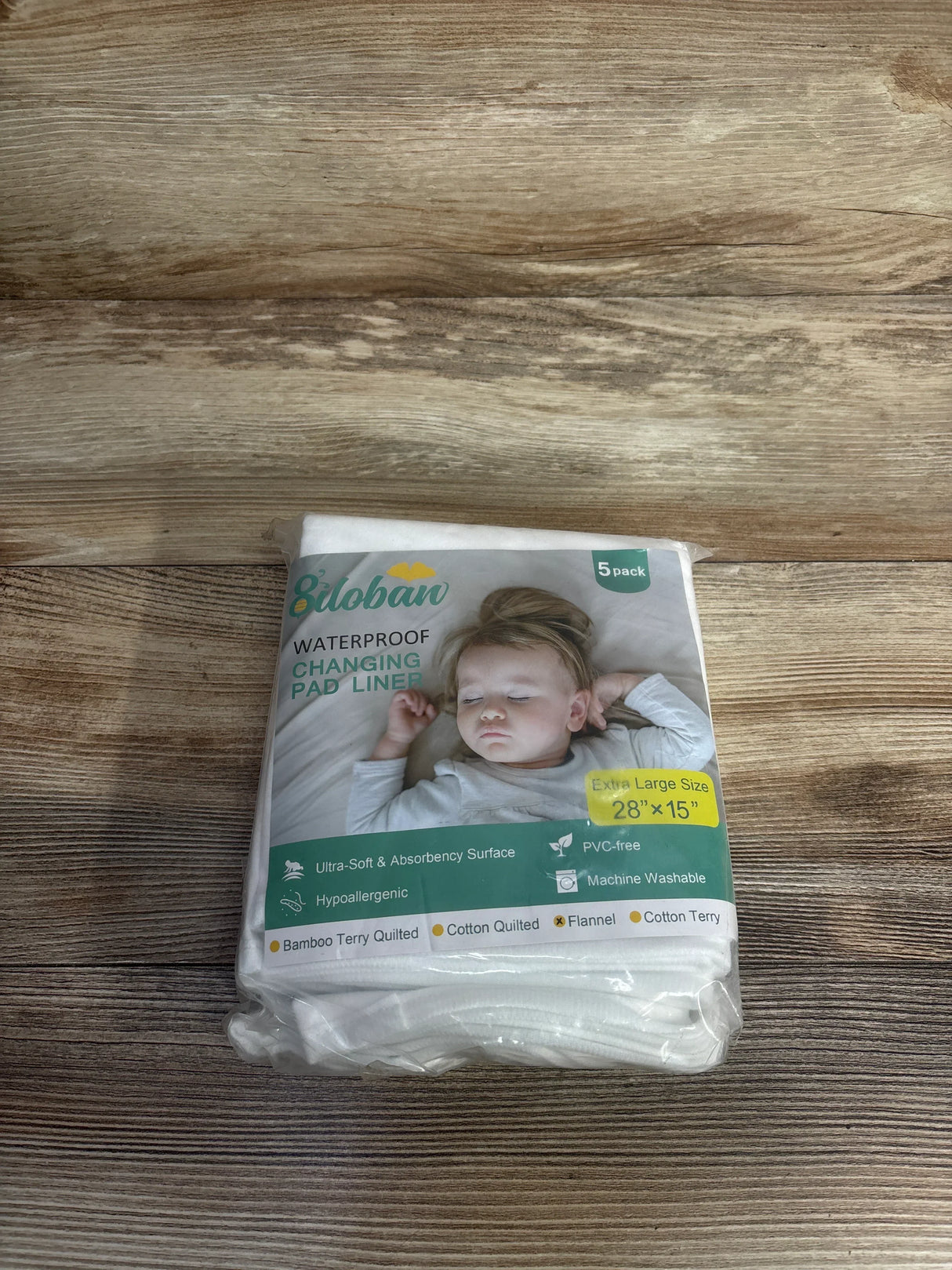 Pack of waterproof changing pad liners for babies, hypoallergenic, machine washable, on wood surface