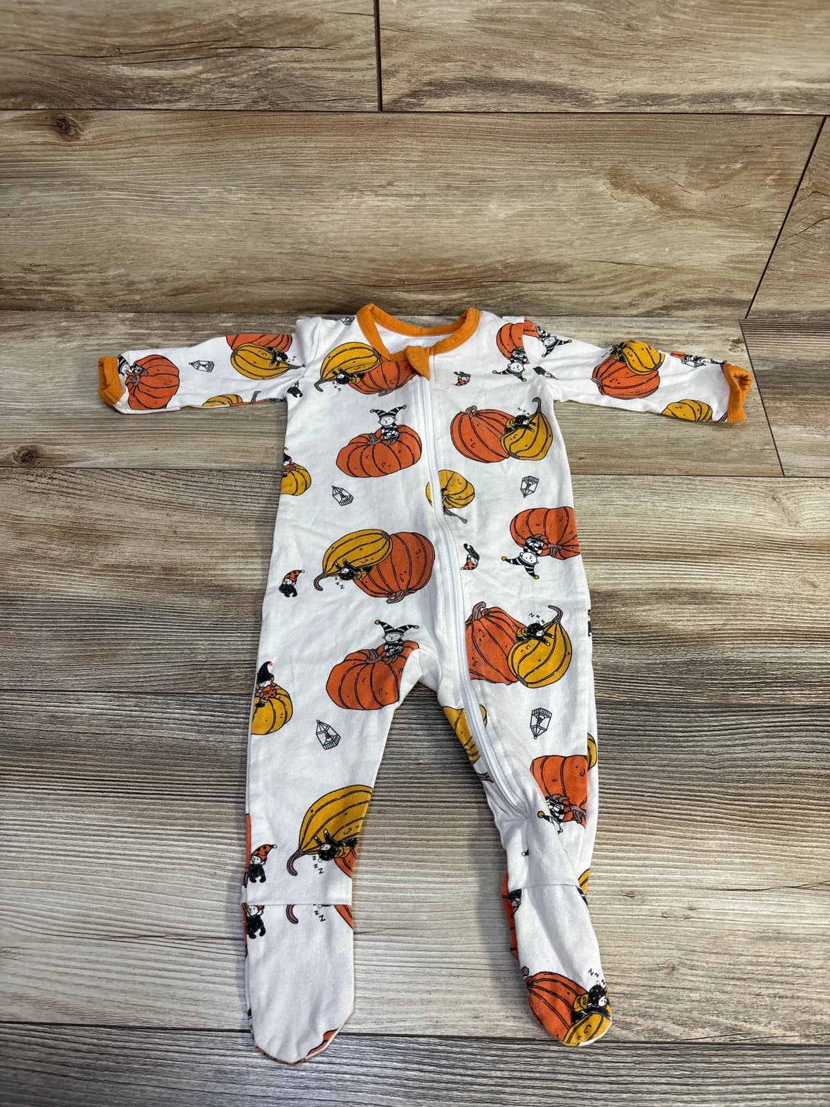 Front view of white YKK Halloween pumpkin sleeper for 0–3 months, showing pumpkin print and zip front on wood flooring