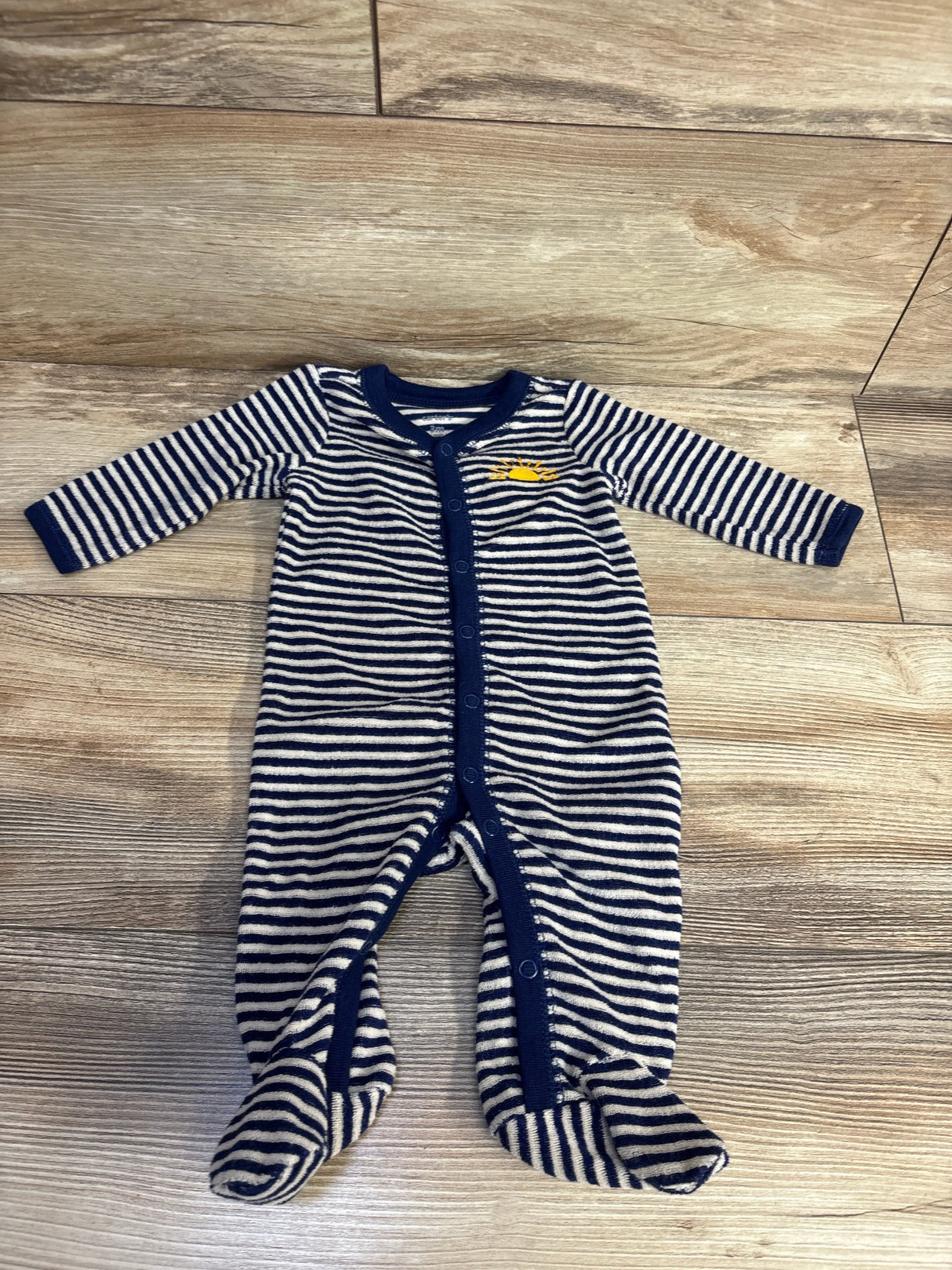 Striped navy and white footed baby sleeper with yellow whale embroidery on wood floor