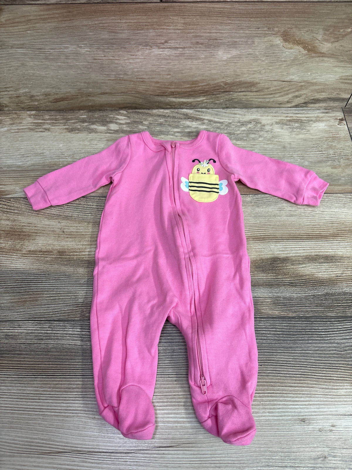 Front view of pink Koala Baby Bee sleeper, size 3 months, with bee appliqué, zipper, and footed legs on wood-grain background