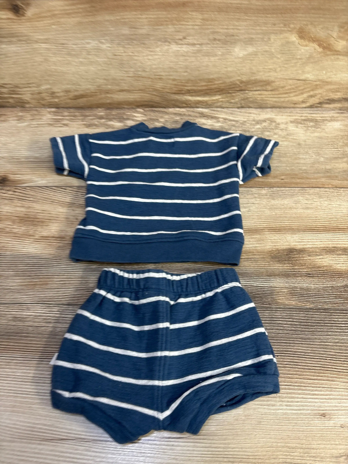 Front view of Little Planet organic striped shirt and matching shorts showcasing horizontal stripes on a wood background
