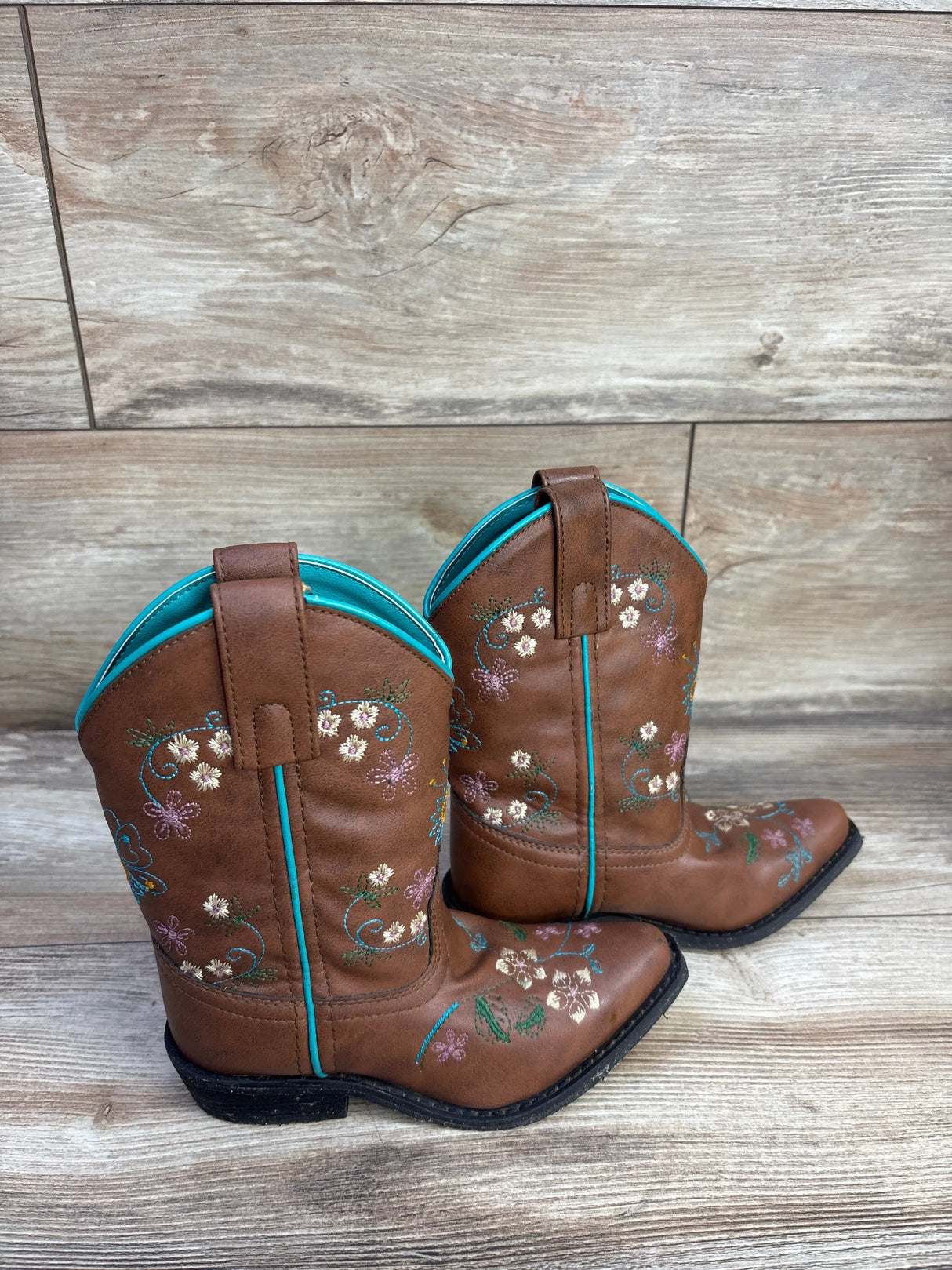 Side view of Shyanne brown floral embroidered western boots showing turquoise trim and multicolor embroidery on wood floor