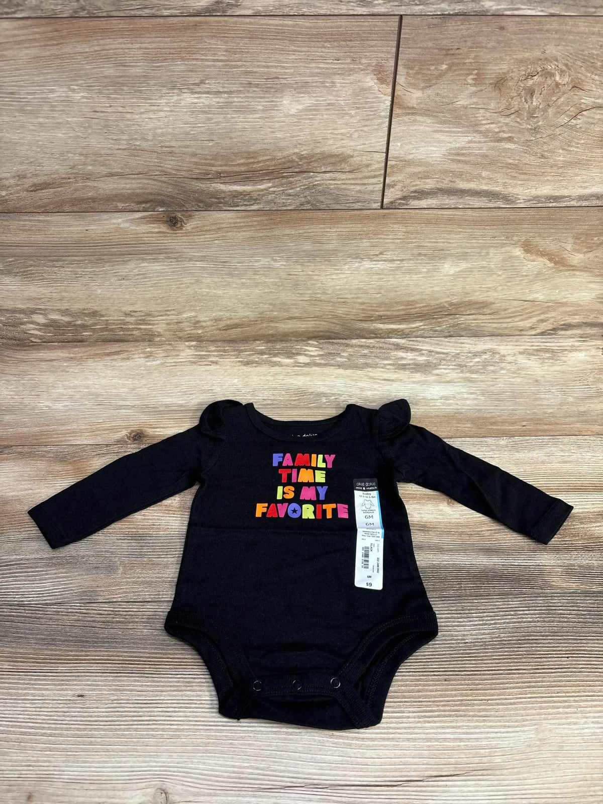 Black long-sleeve baby bodysuit with colorful text family time is my favorite, size 6 months, on wooden floor