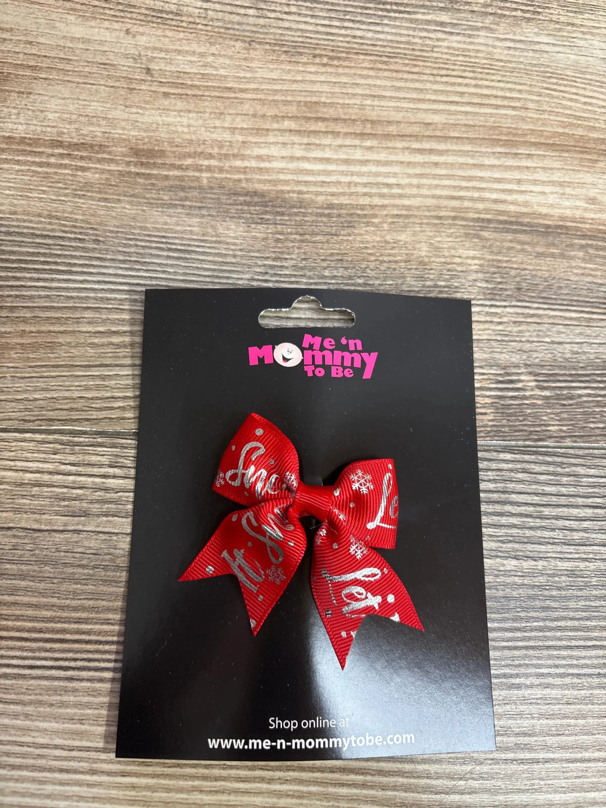 Red holiday bow with snowflakes and 'Let It Snow' text on black card
