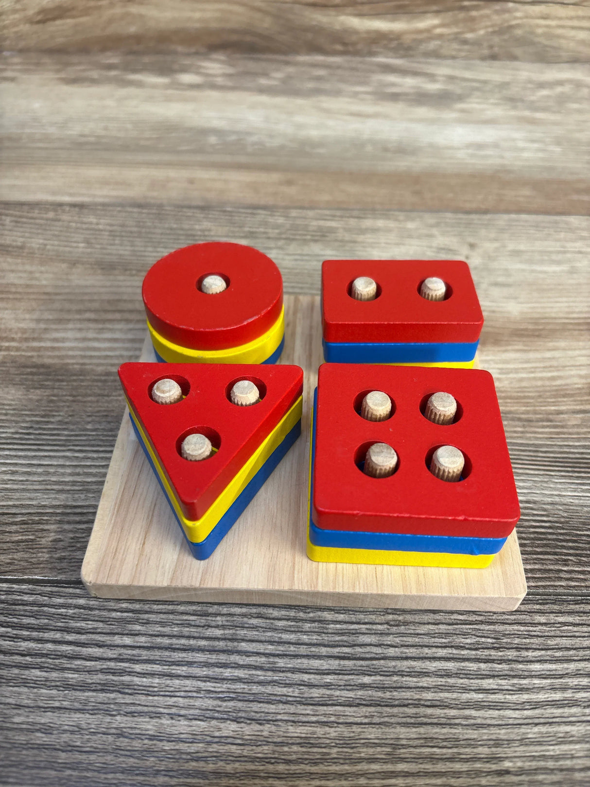 Wooden geometric shape sorting toy with colorful stackable blocks on wooden board