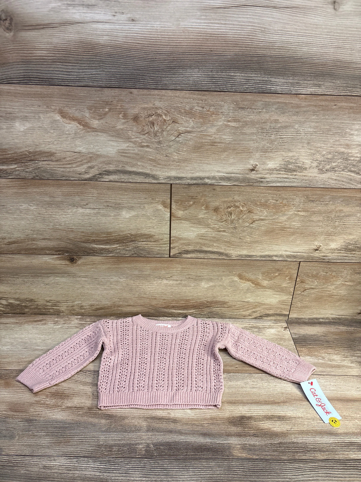 Front flat lay of pink Cat and Jack crochet toddler sweater size 12 months showing openwork knit and ribbed cuffs on wood