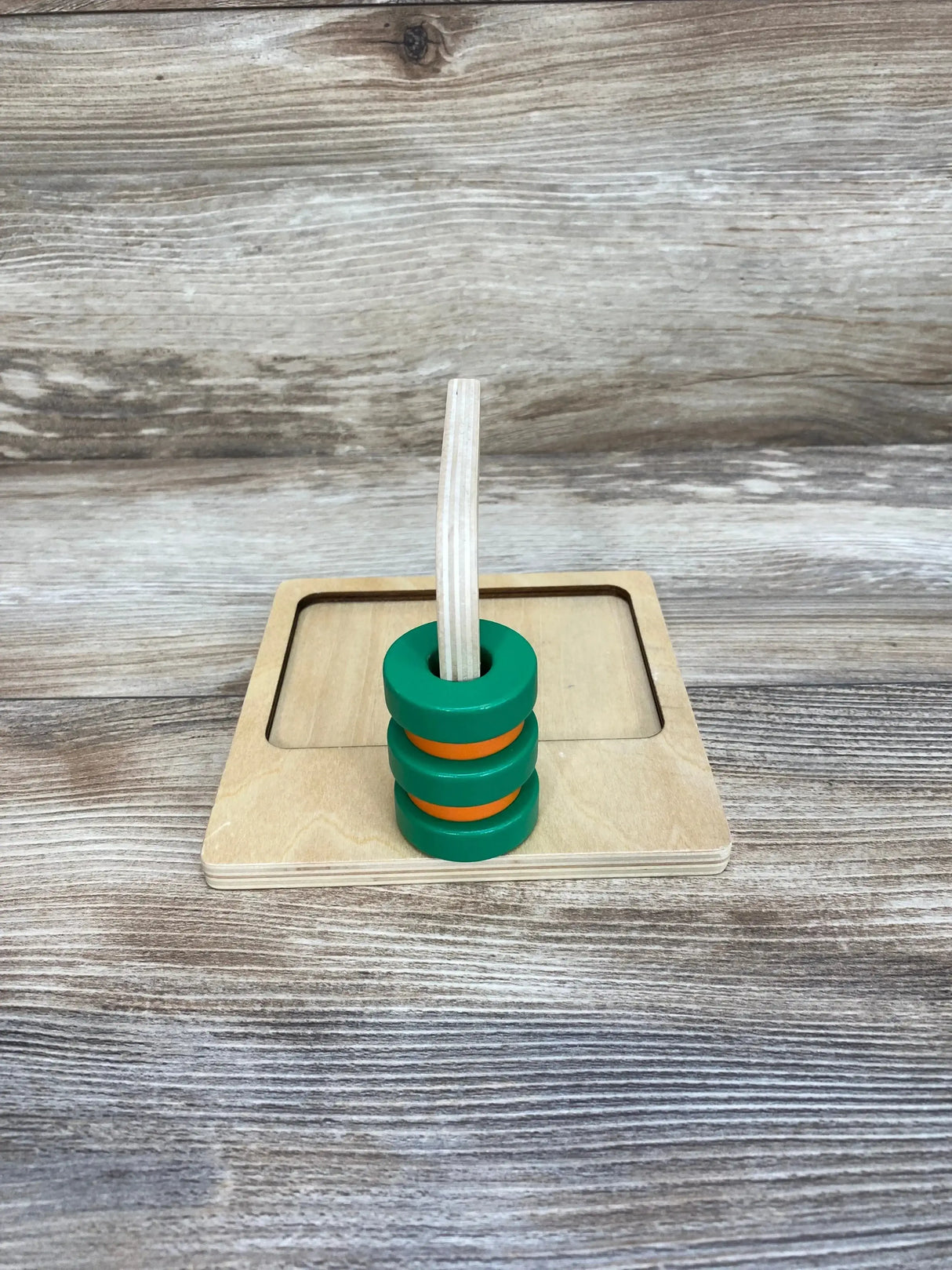 Front view of Monti Kids Curved Dowel showing curved wooden dowel with three green and orange rings on a plywood base