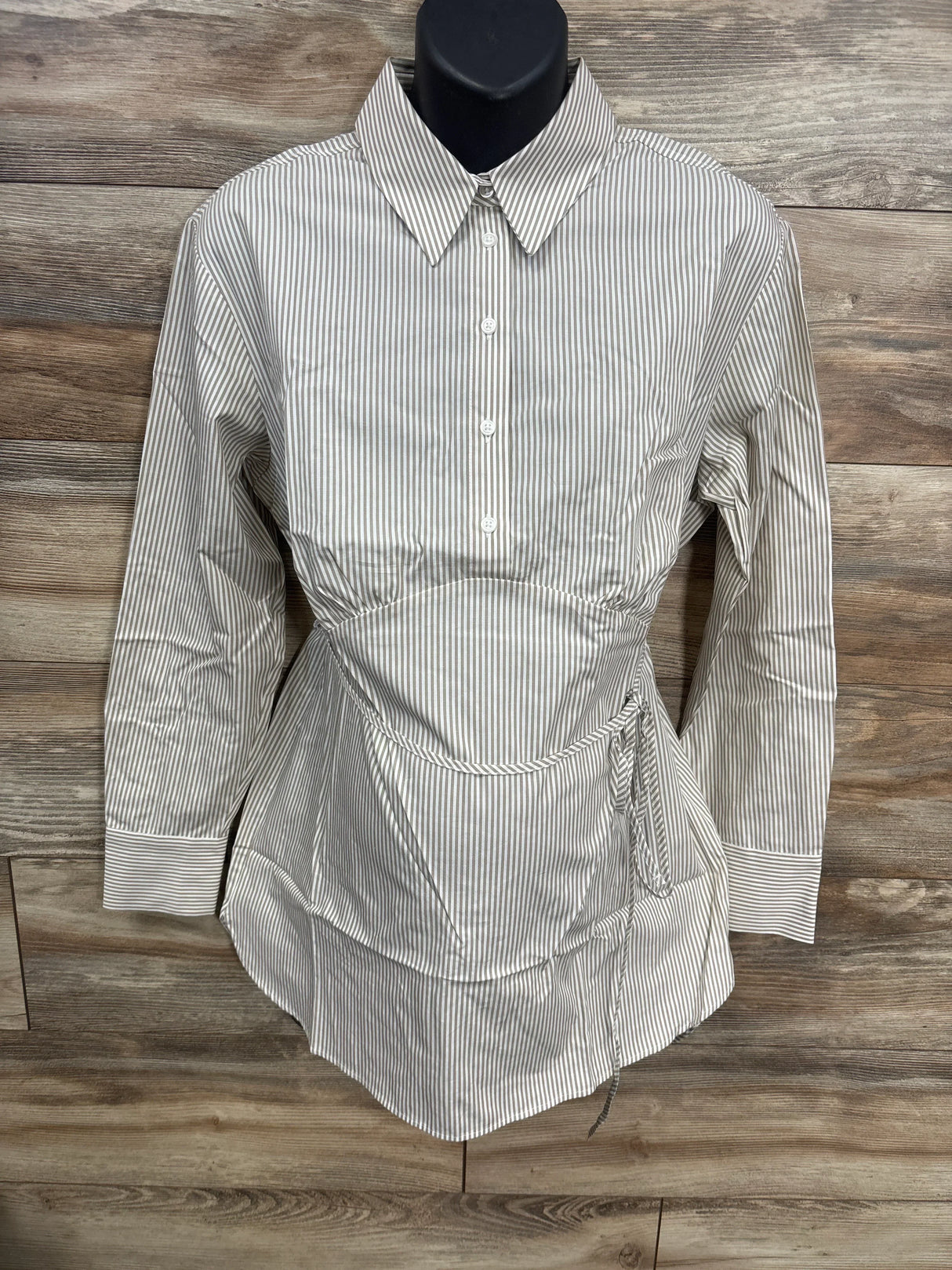 Striped button-up maternity blouse with tie waist and long sleeves on wooden background