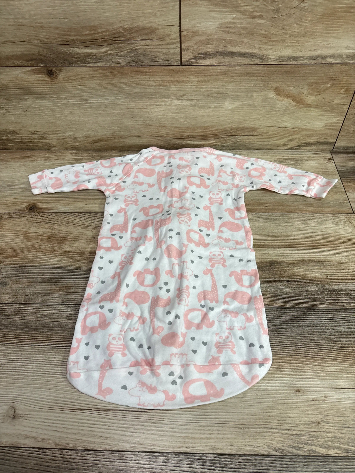 Front view of The Peanutshell sleep sack showcasing a pink animal print and long sleeves on a wood floor