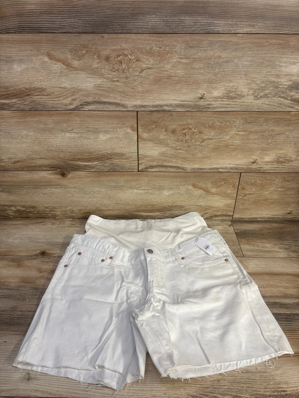 Front view of white Gap maternity denim Bermuda shorts showcasing full panel and five-pocket styling on a wood floor