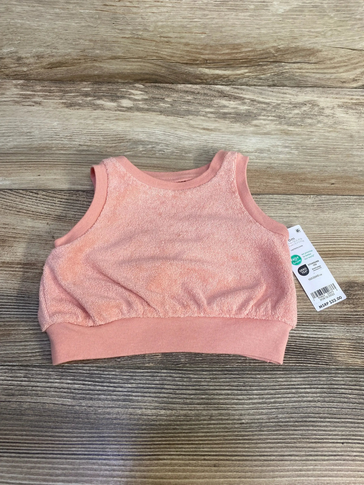 Front flat-lay of Carter’s pink terry cloth baby tank top showing ribbed elastic hem and sleeveless design on wood background