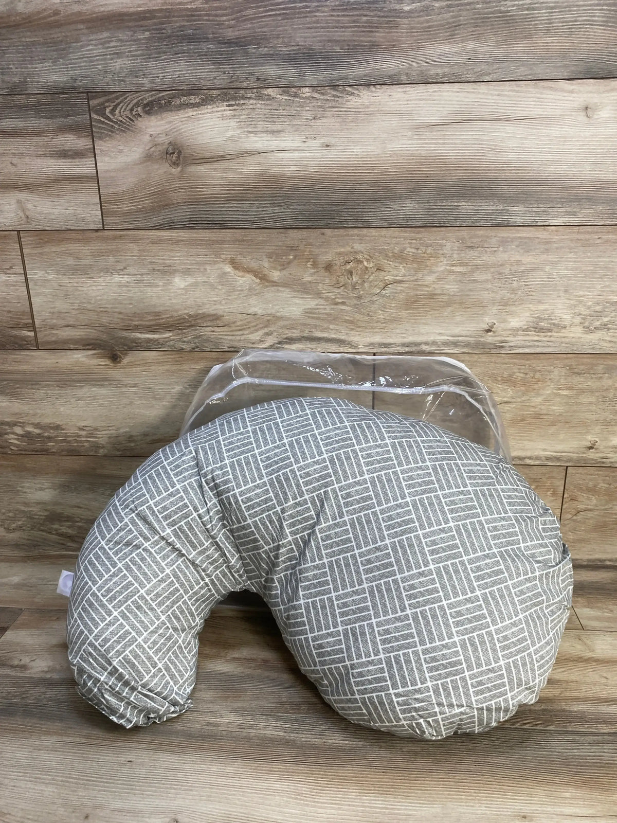 Front-angle of Boppy Cuddle pregnancy pillow showcasing gray basket weave slipcover and C-shape on wood plank background