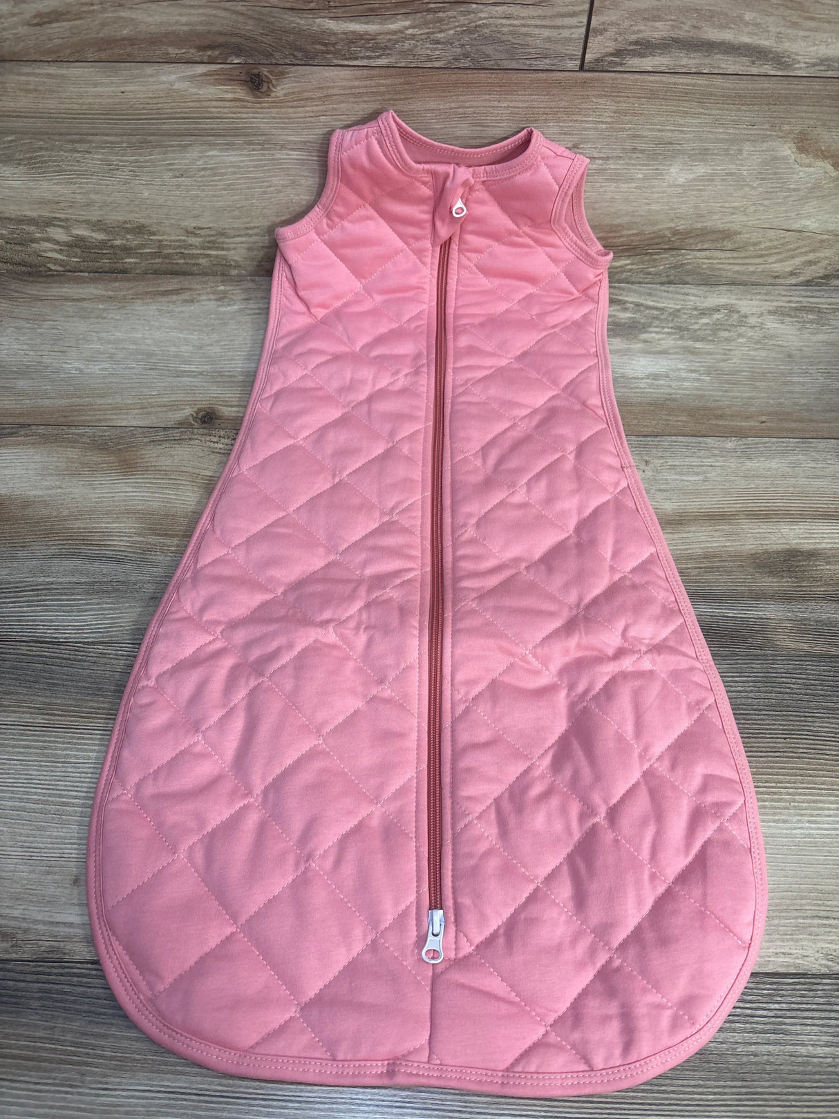 Pink quilted baby sleep sack with zipper on wood floor