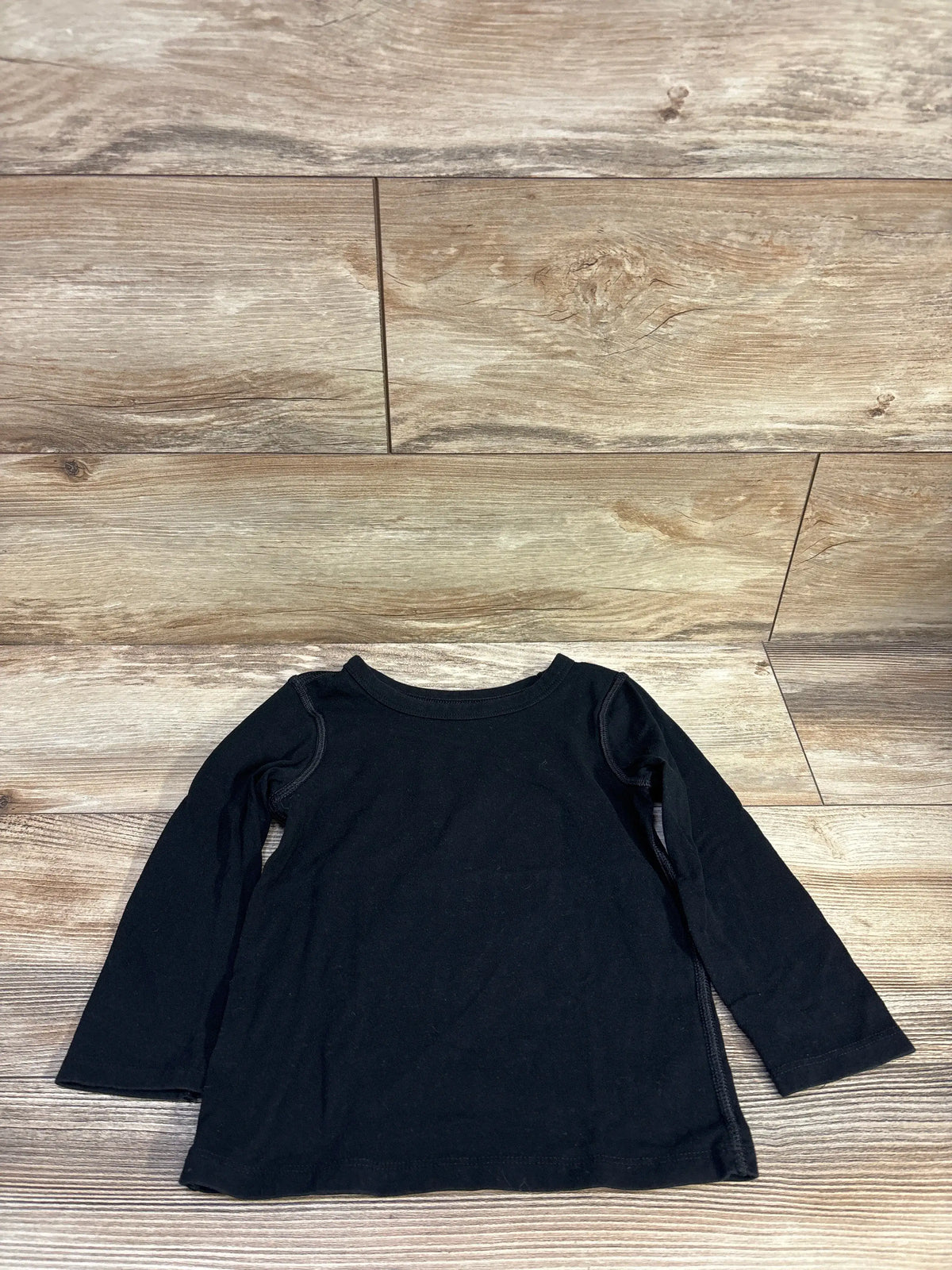 Front flat lay of Cat and Jack black long-sleeve toddler shirt (size 4T) showing crew neck and long sleeves on wood plank background