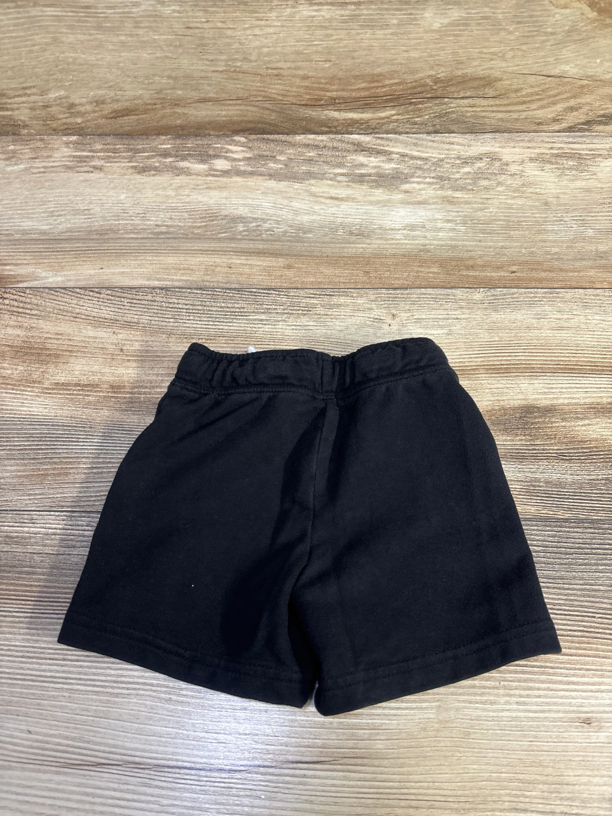 Flat-lay front view of Cat & Jack black knit toddler shorts showing elastic waistband and straight hem on wood floor background