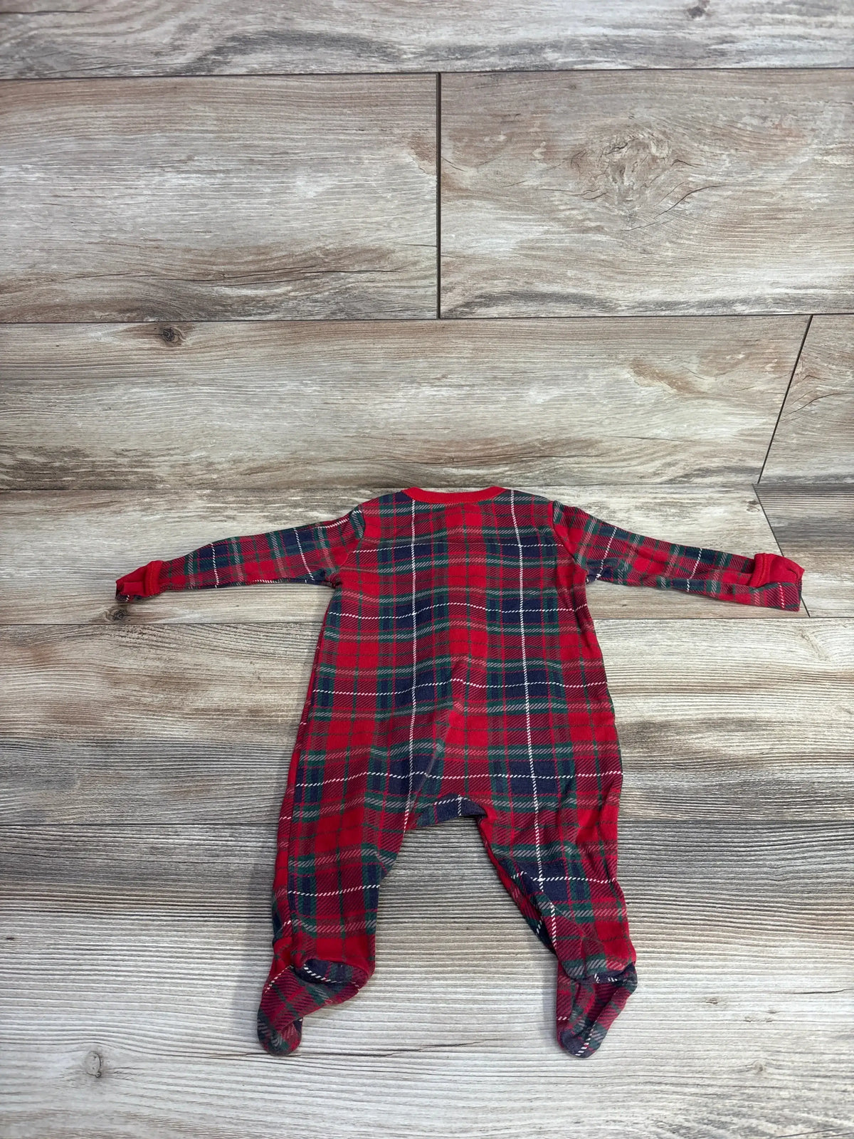 Red and green plaid baby footed pajamas on wood floor, holiday kids clothing