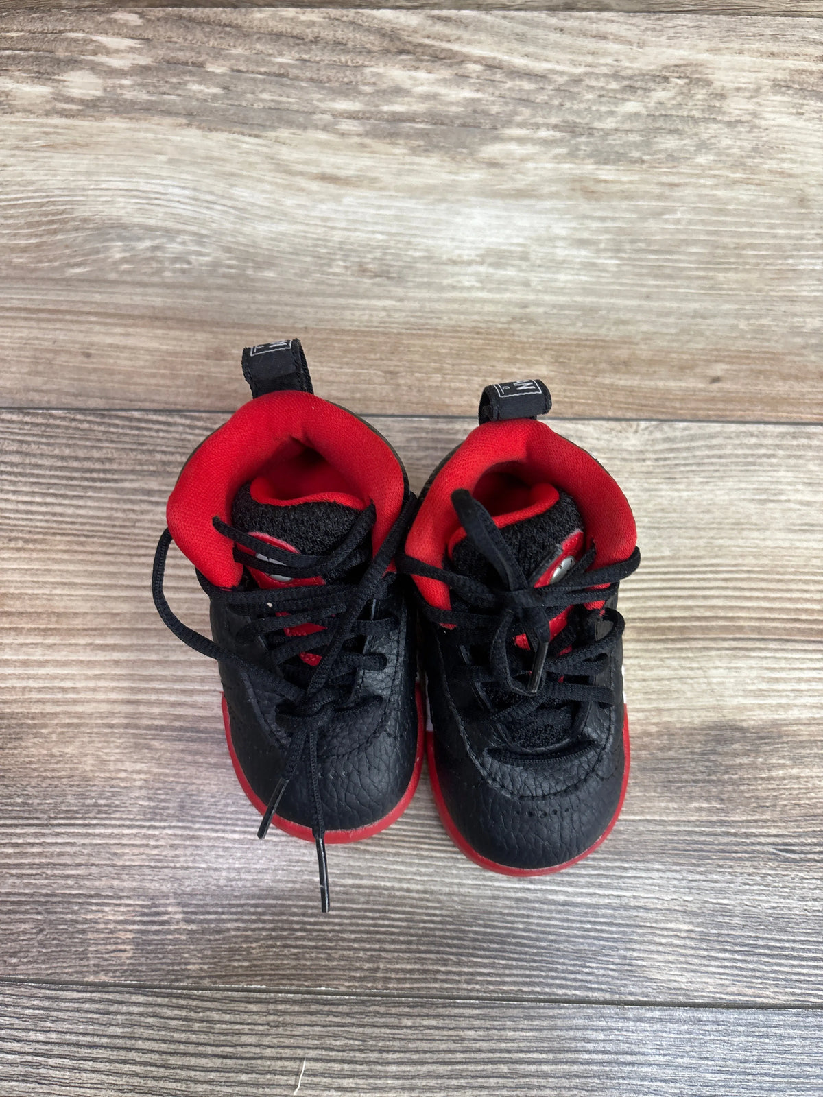 Top view of Air Jordan Jumpman Pro TD Bred sneakers showcasing black and red color blocking with a wood-grain background