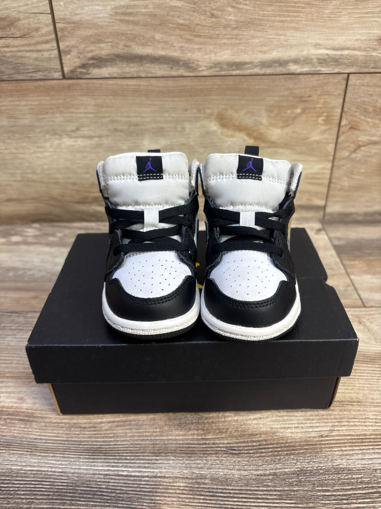 Front view of Jordan 1 Mid Hologram sneakers, size 6C, black and white with purple Jumpman on tongue, on black shoebox