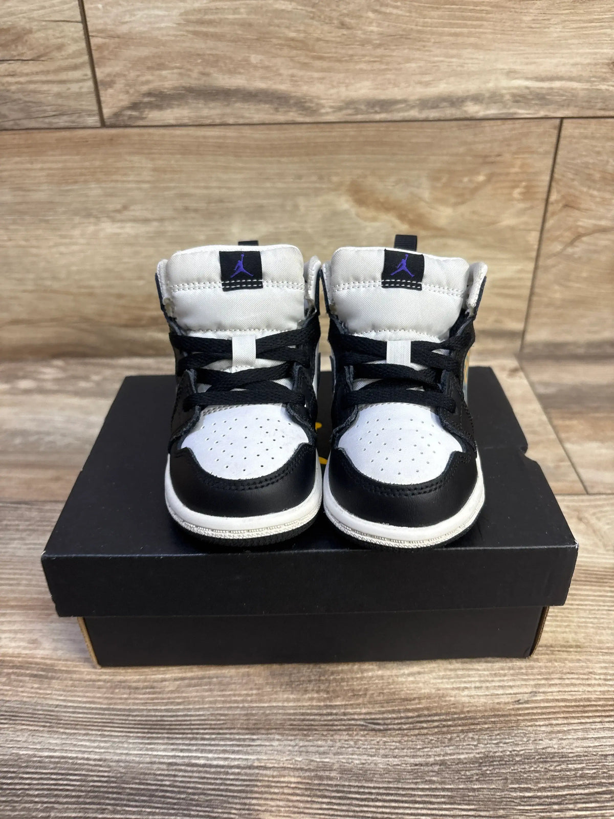 Front view of Jordan 1 Mid Hologram sneakers, size 6C, black and white with purple Jumpman on tongue, on black shoebox