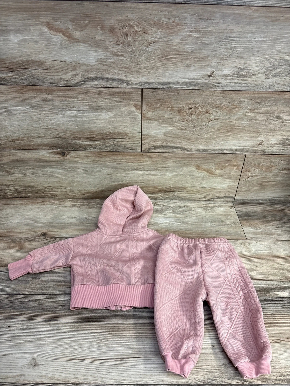 Top-down view of 2pc Textured Full Zip Jacket and Bottoms Set in rose gold showcasing the textured pattern on a wood-look floor