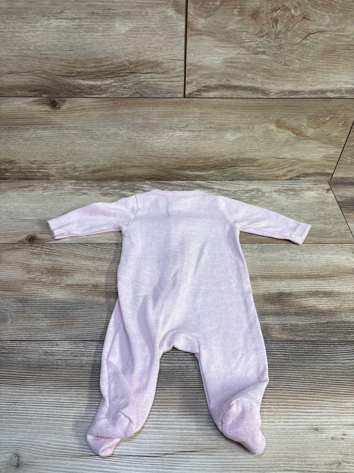 Back view of Old Navy knit footed sleeper in light pink showcasing long sleeves and built-in feet on wood background