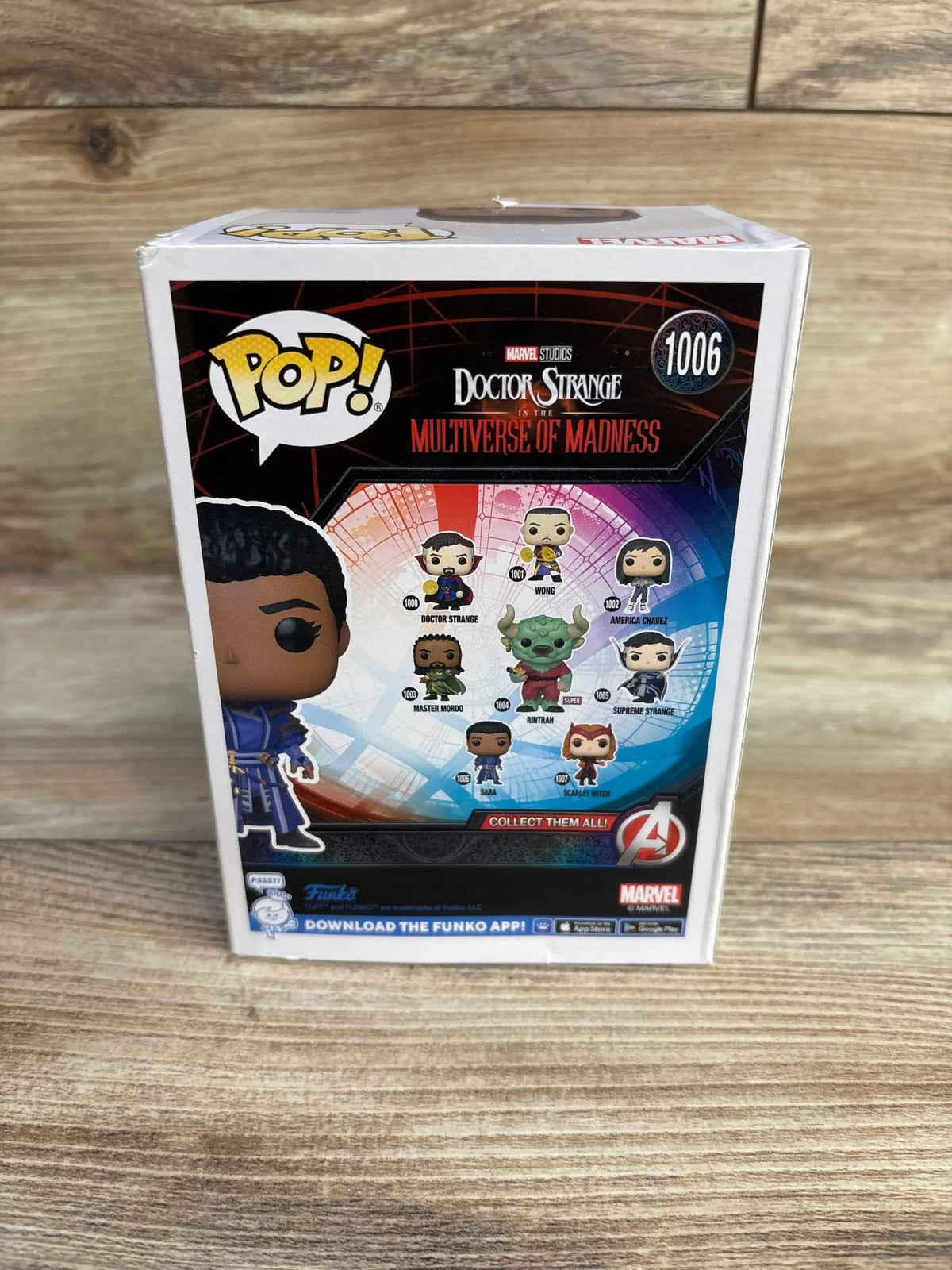 Back view of Funko Pop Sara box showcasing Multiverse of Madness character lineup and collectible number 1006 with wooden tabletop background