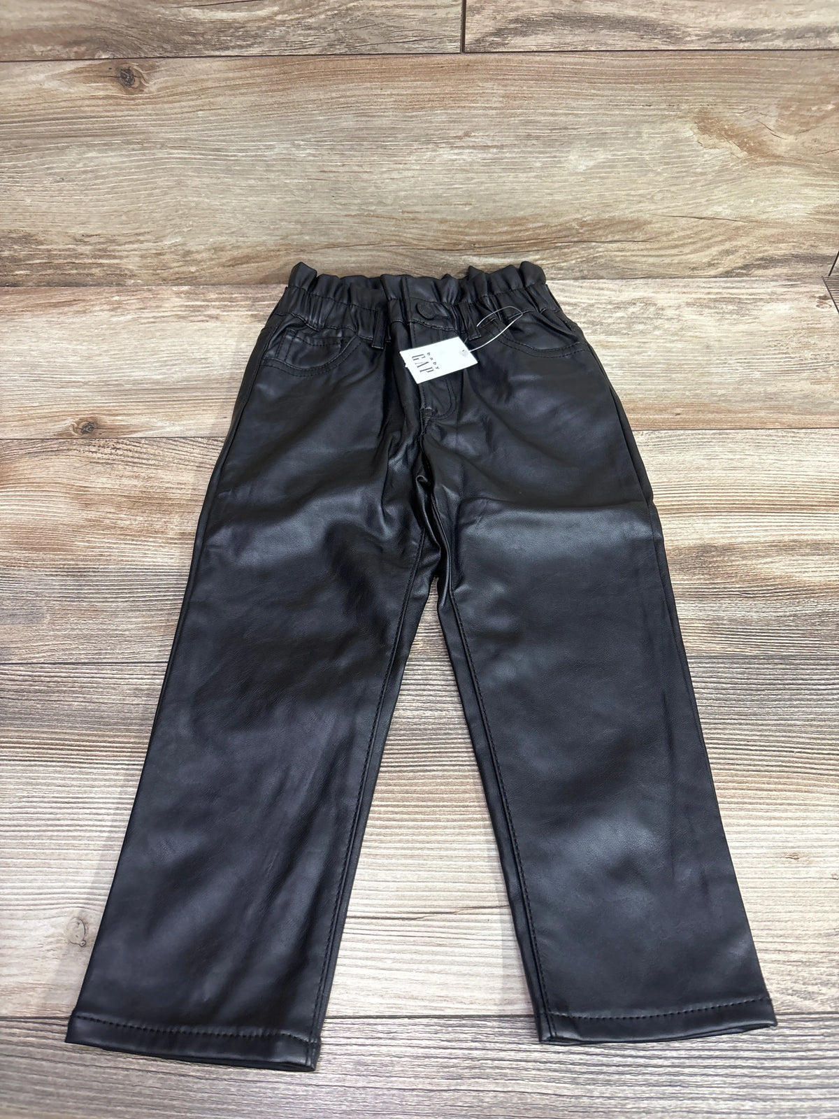 New Baby Gap toddler black faux-leather pants size 4T laid flat on a wood floor