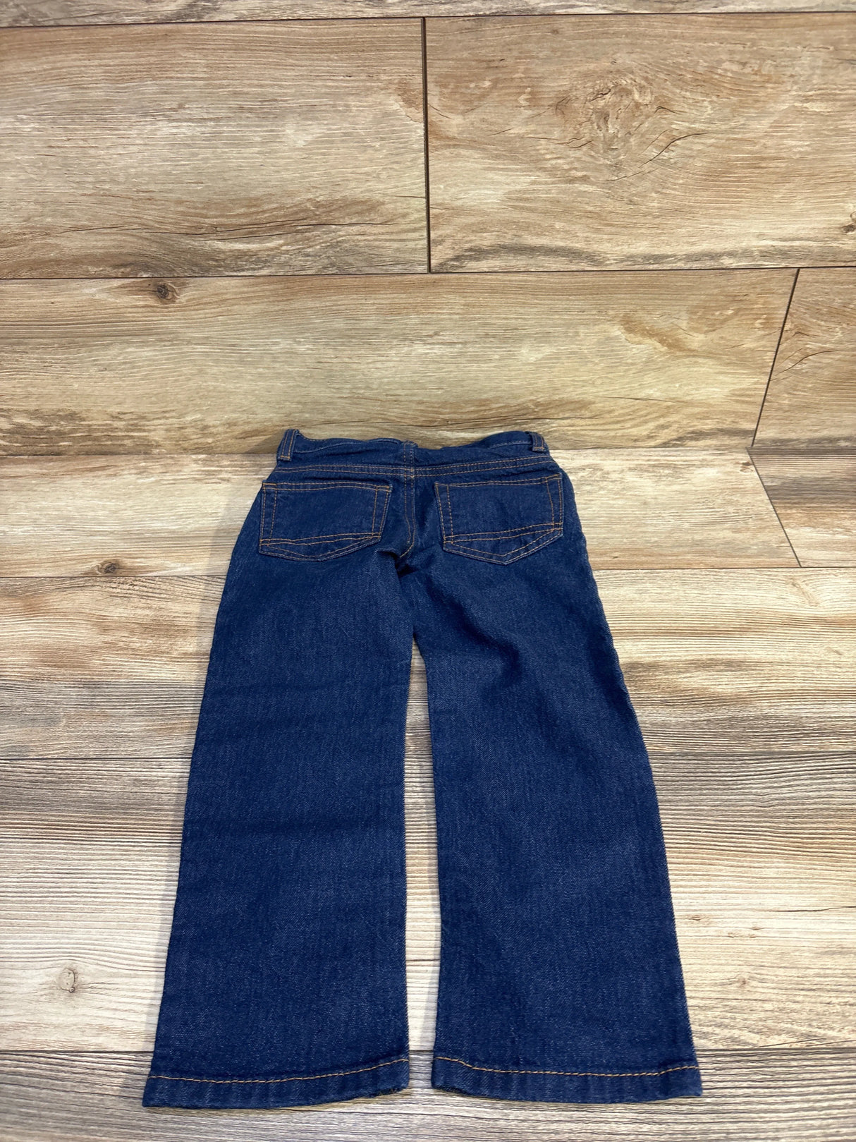 Back view of Cat and Jack toddler straight-leg jeans showing back pockets and dark blue denim on wooden floor background