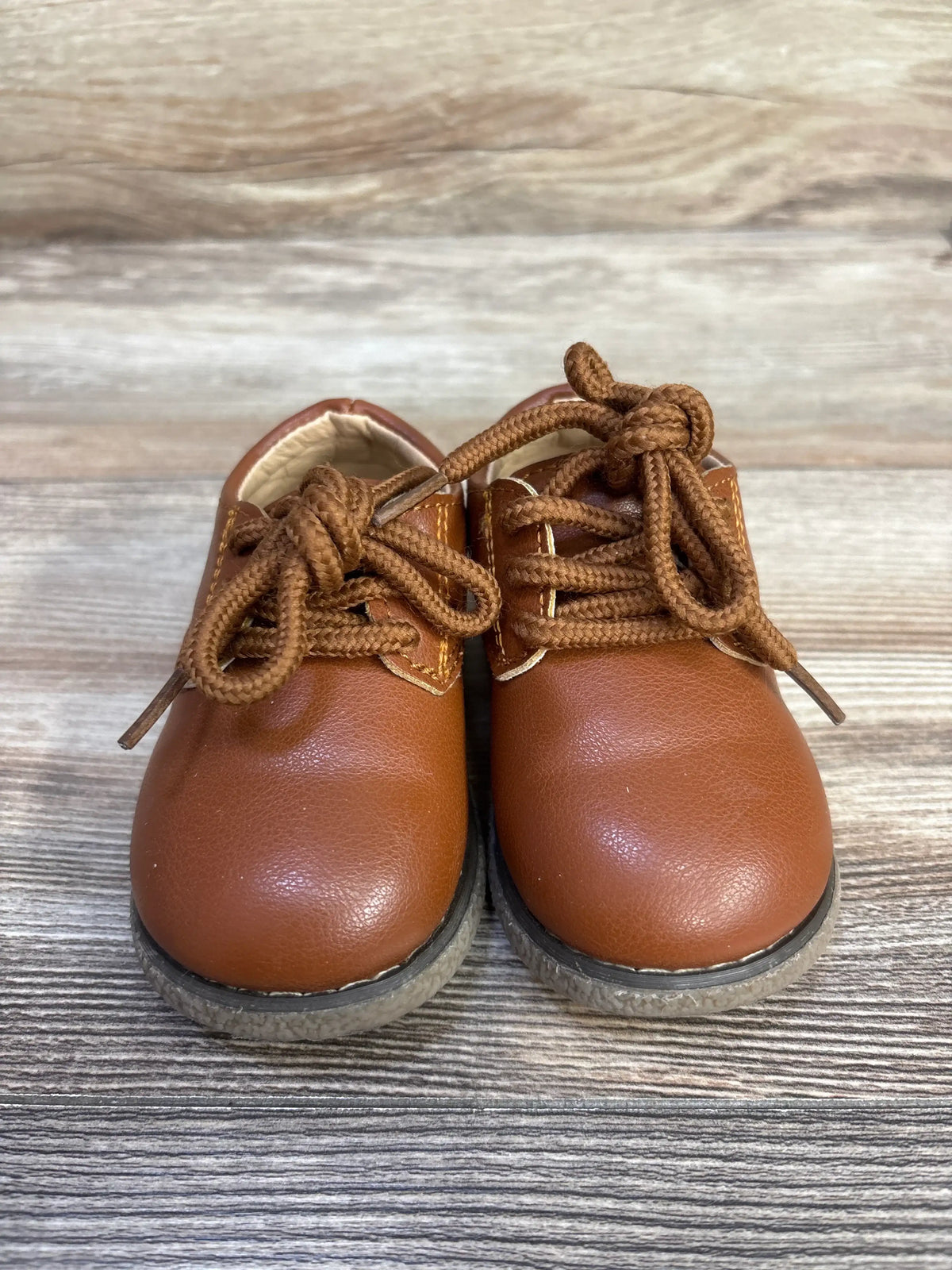 Front view of Meckior Oxford dress shoes in brown, showcasing lace-up PU leather uppers on a wood-grain background
