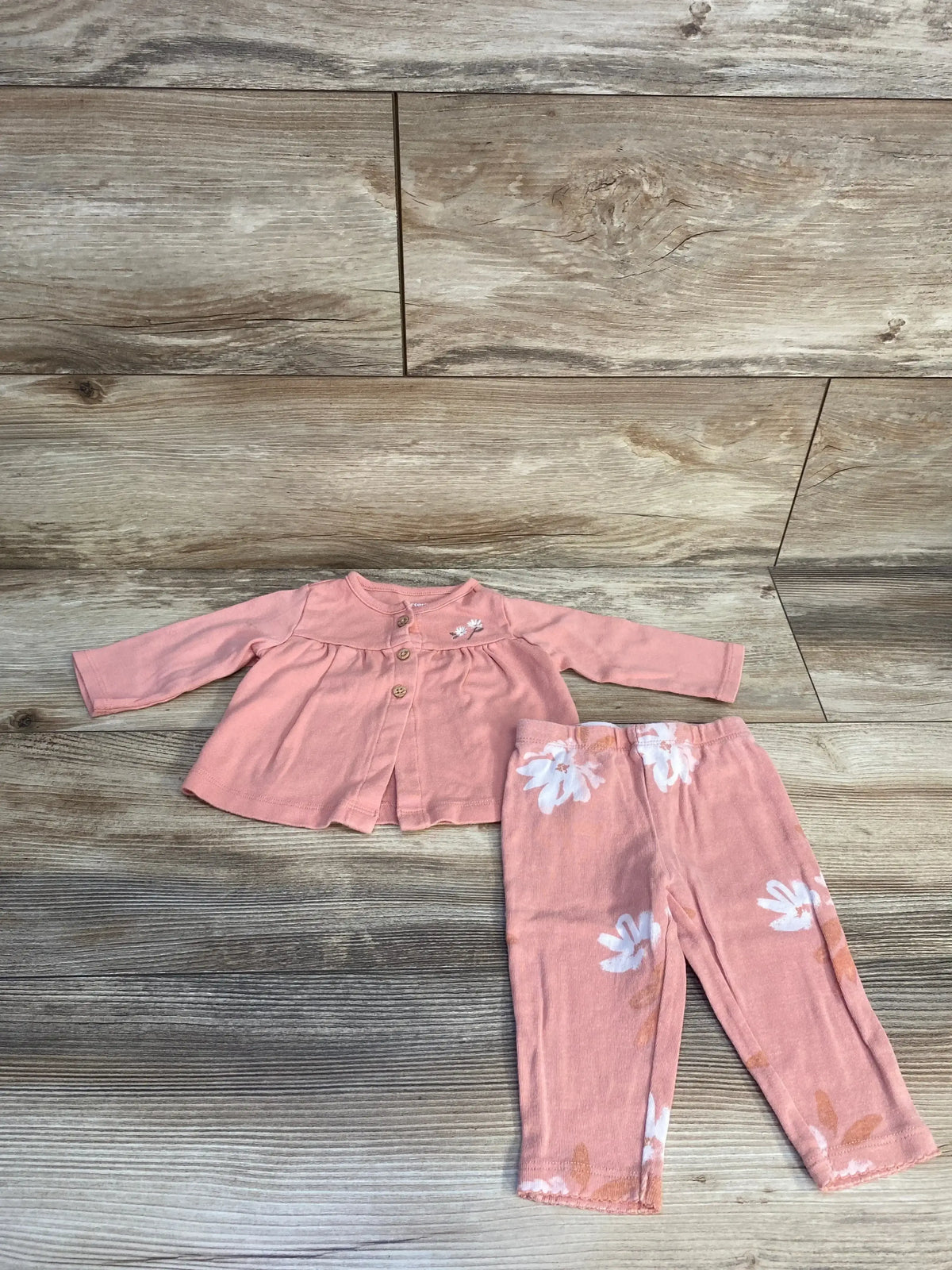Pink baby outfit set with long sleeve top and floral pants on wood background