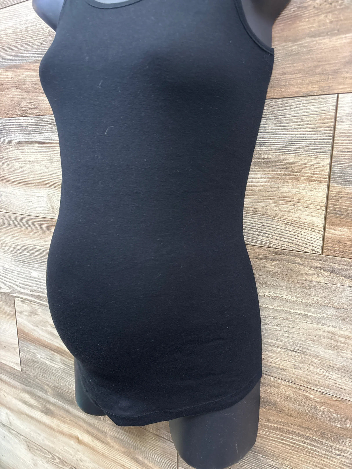 Black maternity tank top displayed on a mannequin against wood panel background at kids resale store