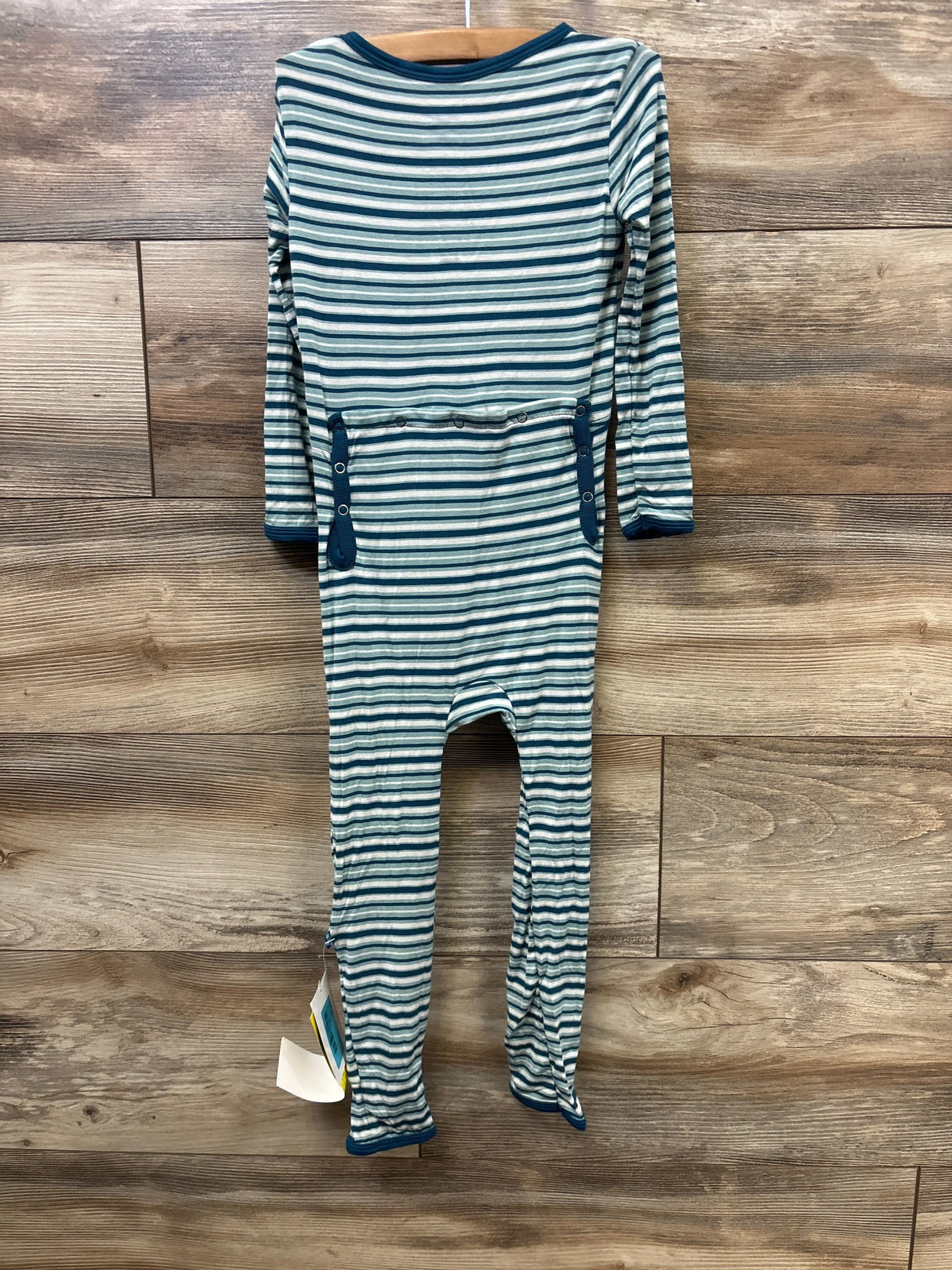 Long sleeve blue and white striped baby romper with side snaps, hanging on wooden wall