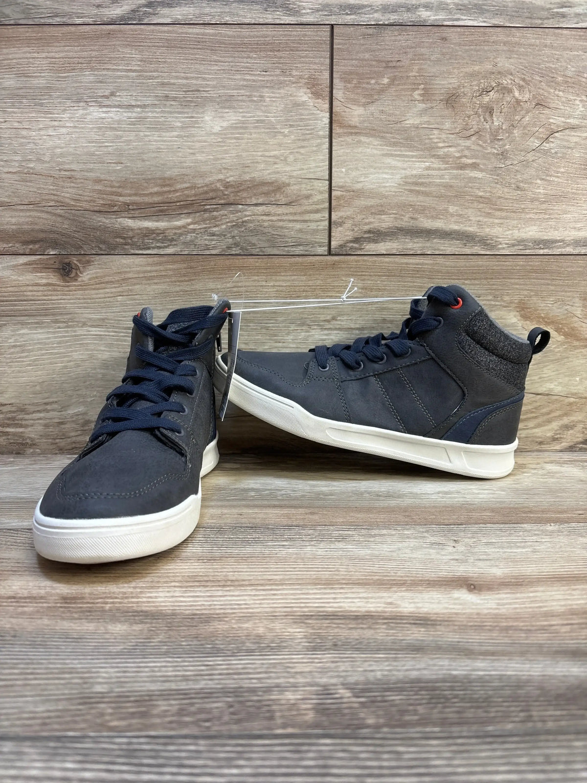 Angled front view of Art Class Geoff grey high-top kids sneakers (size 6Y) showing padded ankle collar, navy laces and white rubber soles on wood background