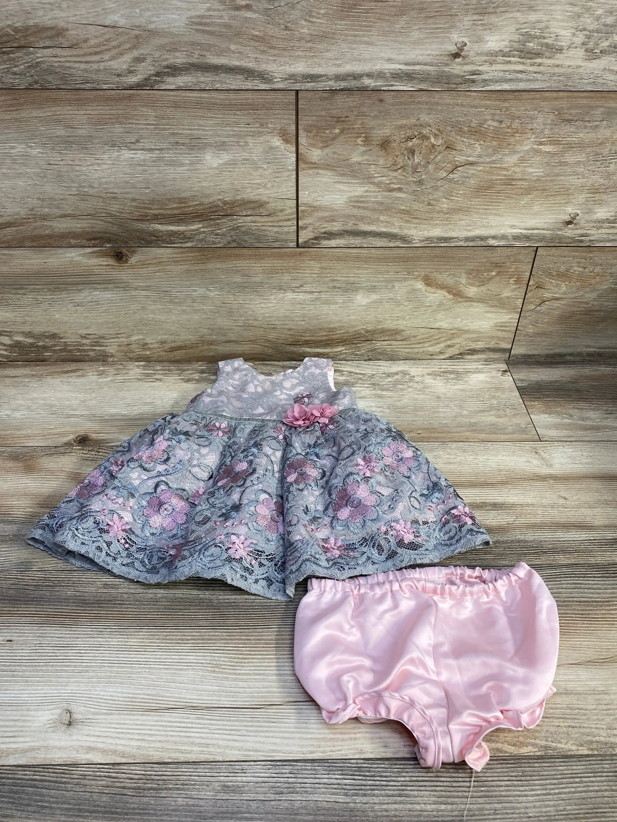Overhead view of Laura Ashley 2-piece lace floral dress and bloomers showcasing a sleeveless grey dress with pink bloomers on a wood floor