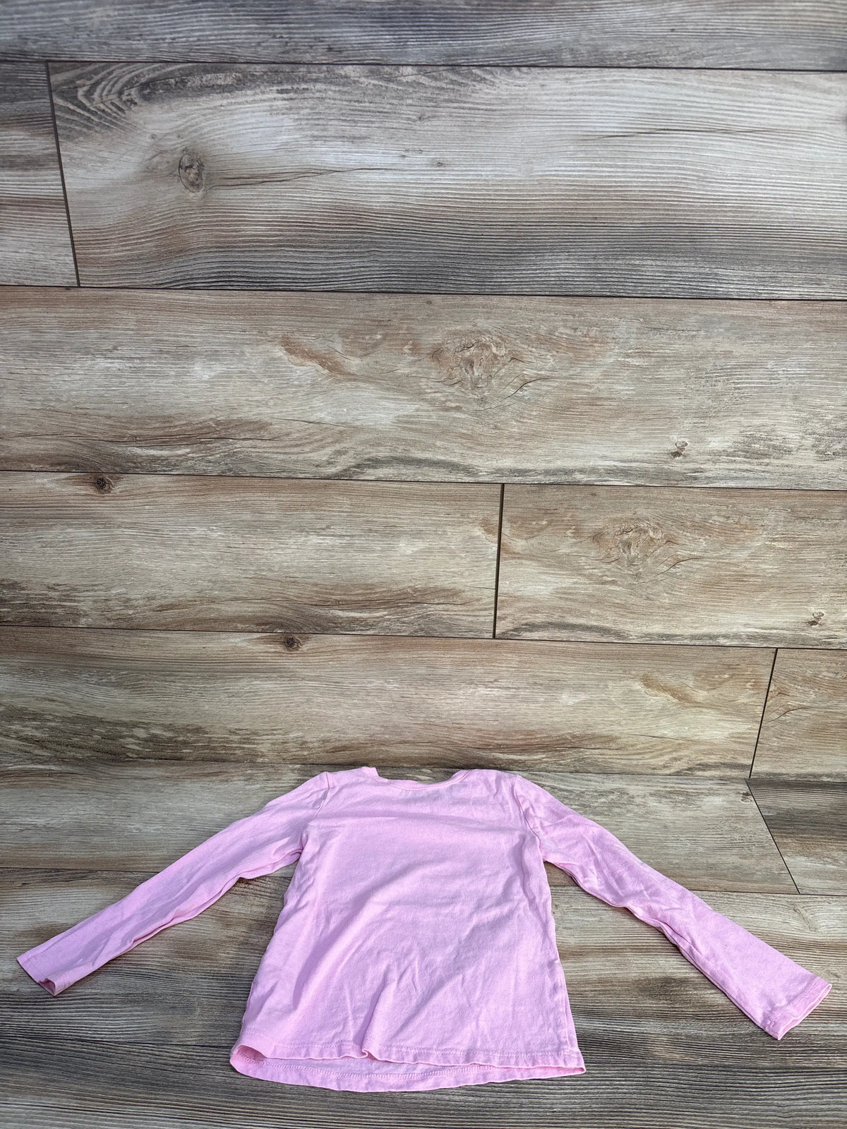 Back view of Children’s Place pink long-sleeve shirt showcasing its relaxed fit on a wood-look floor
