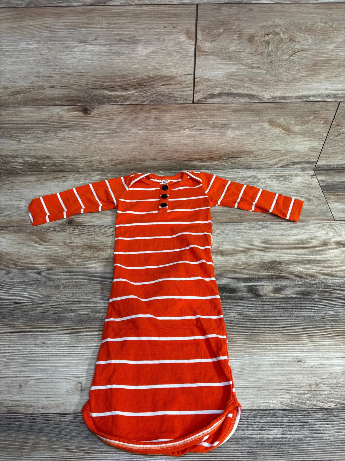 Flat lay of orange and white striped Henley sleeper gown, size 3-6M, showing three-button placket on wood floor