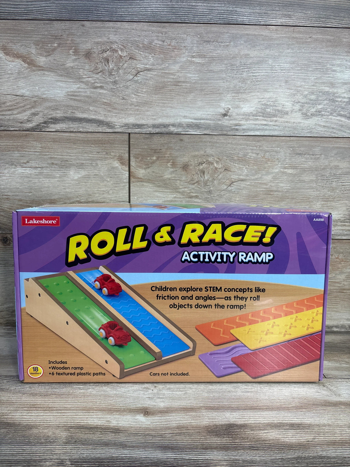 Front view of Lakeshore Roll & Race activity ramp box showing wooden ramp and colorful textured track inserts on wood backdrop