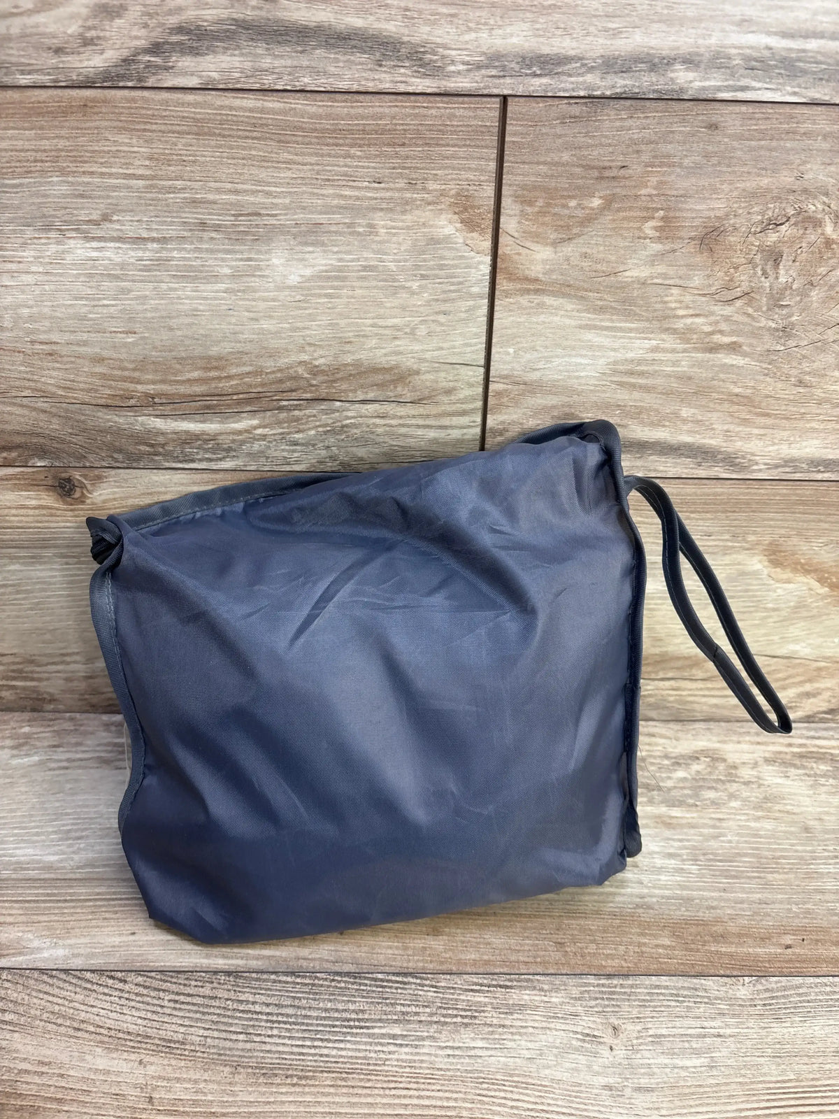 Front view of Icopuca car seat cover folded inside its grey storage pouch with wrist strap on a wood plank background