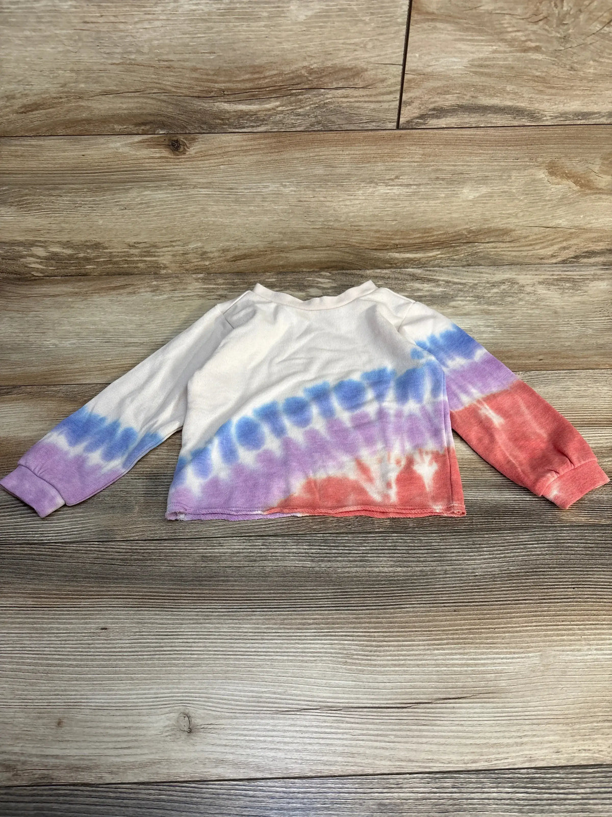 Kids long sleeve tie-dye shirt with blue, purple and red pattern on wood background