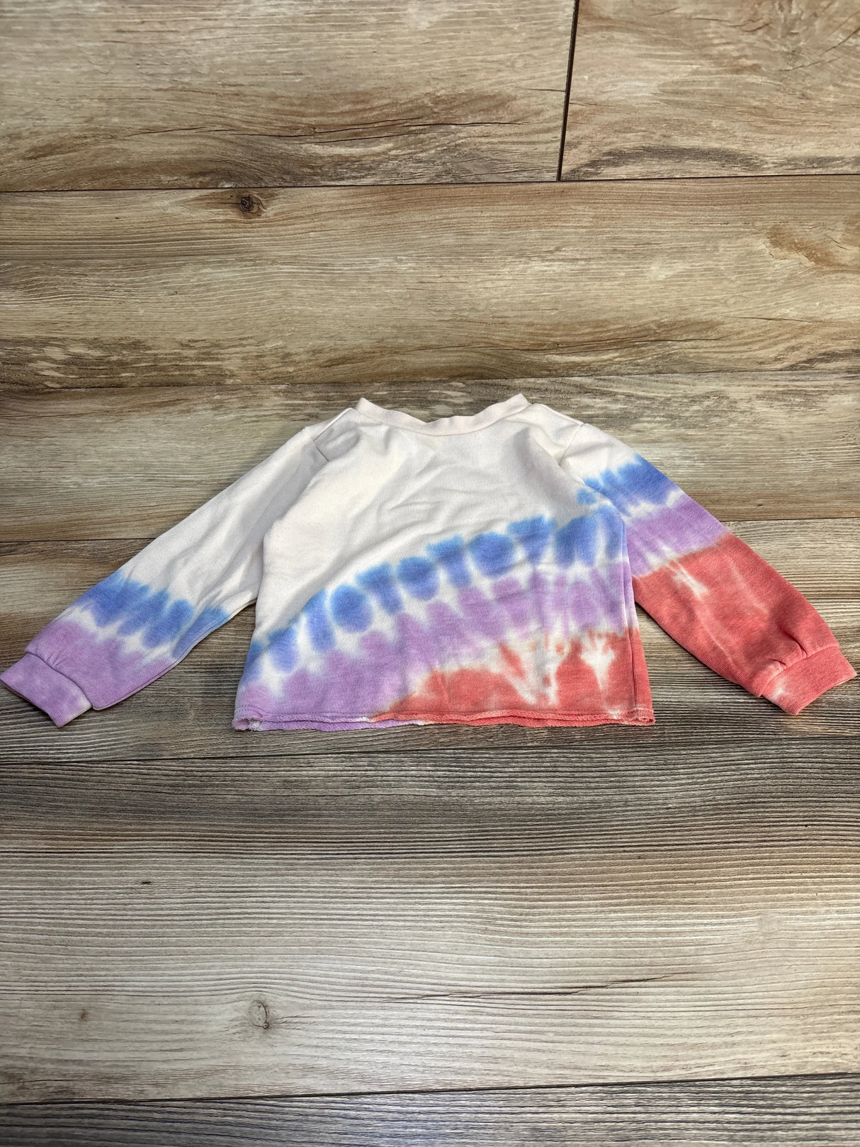 Kids long sleeve tie-dye shirt with blue, purple and red pattern on wood background