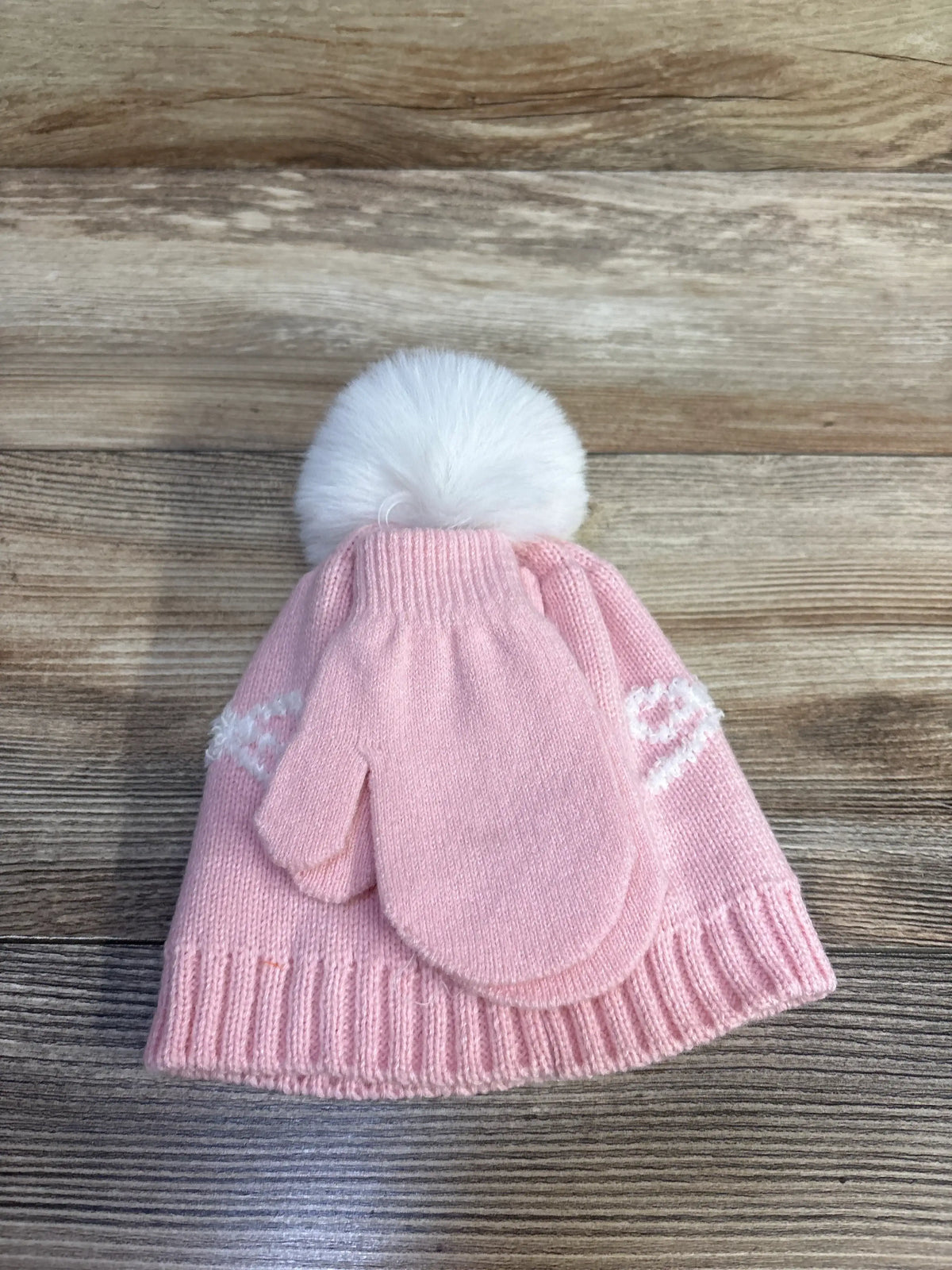 Front view of Capelli New York pink hat and mittens set showcasing white pom-pom and patterned bands on wood