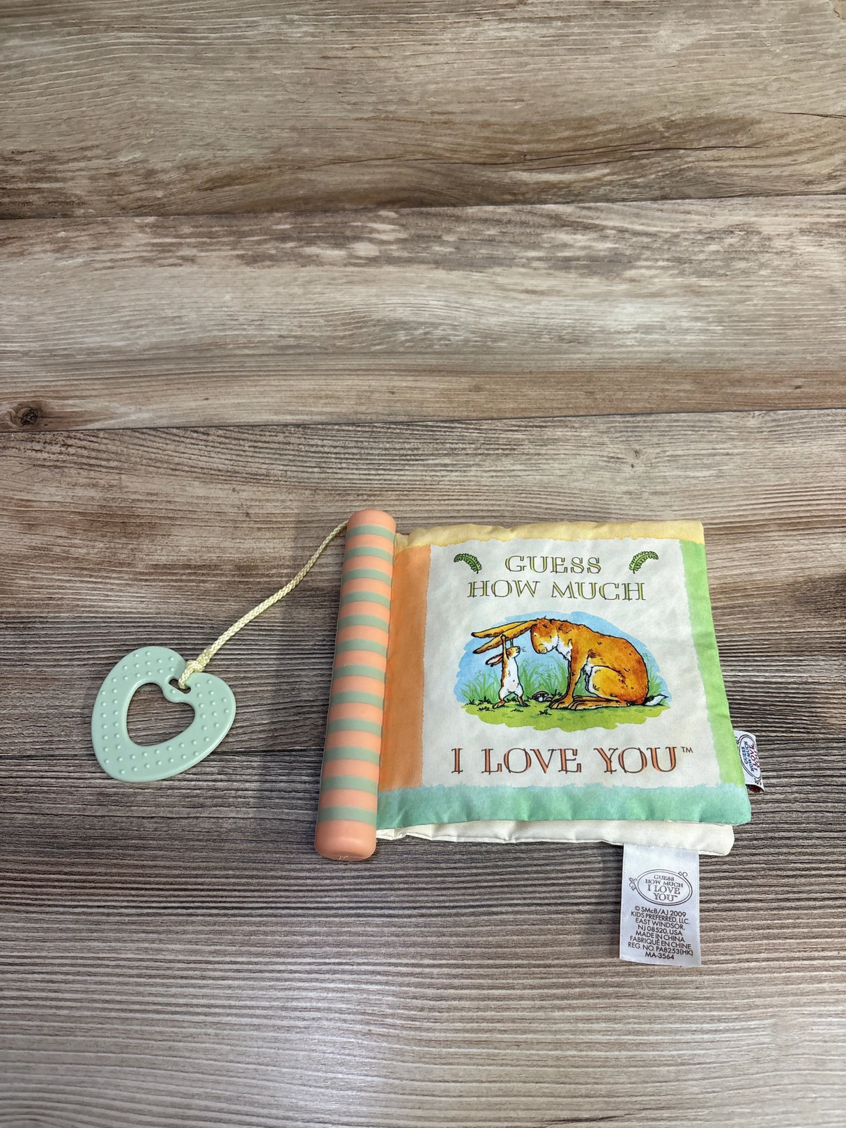 Soft baby book with teether, Guess How Much I Love You cover illustration on wood background