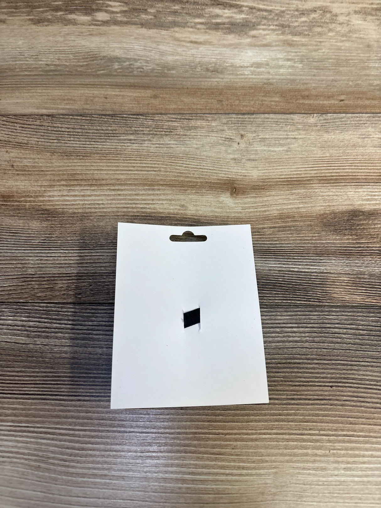 White product tag with hang hole on wood surface, for kids or maternity items