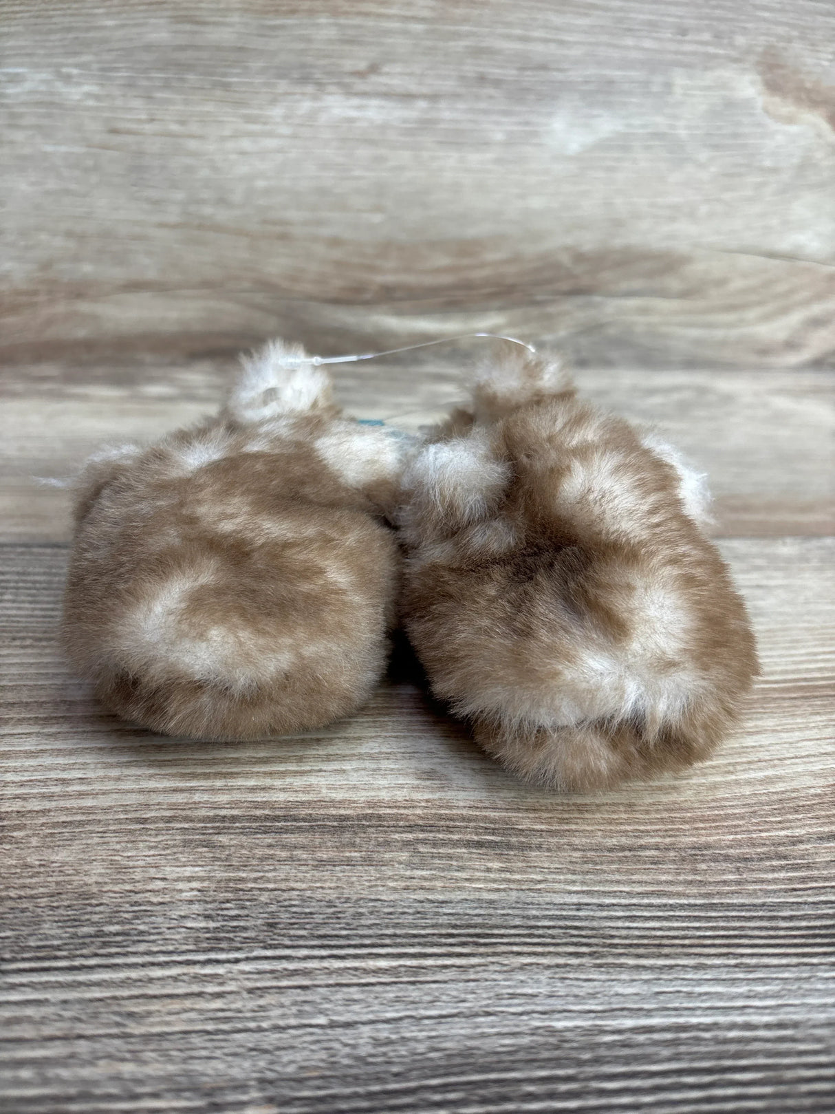 Soft and fluffy brown baby mittens on wood background for children's resale store